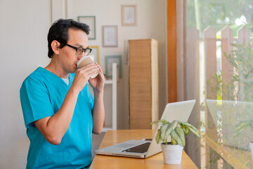 Smiling nurse using digital tablet in employee lounge. Male nurse takes a break outside of a coffee shop.