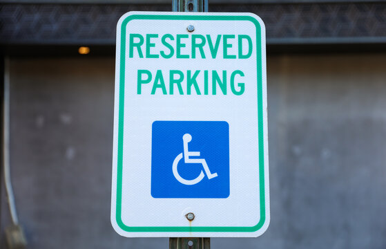 handicap parking sign in blue and white on a paved lot, symbolizing accessibility and inclusivity in urban spaces