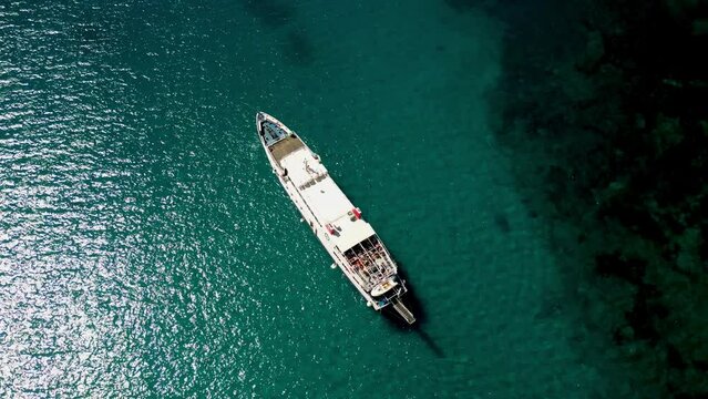 Rounded aerial view of cargo ship in azure trasparent clear sea water