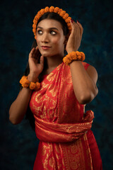 portrait of a tribal woman wearing orange flower garland and orange saree 