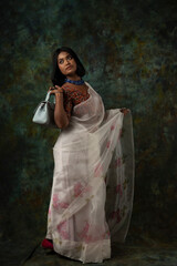 a woman wearing white saree and blue necklace holding harp/veena in hand and handbag promoting peace and harmony 