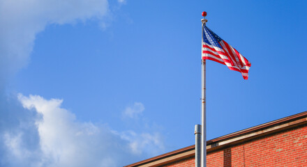US flags waving against clear blue sky, symbolizing patriotism, unity, freedom, and national pride in a bustling cityscape