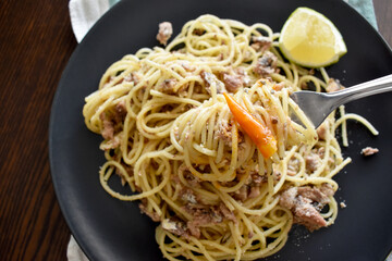 Spicy sardine pasta on fork on a plate. Flat lay top view photo.