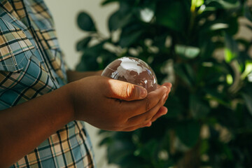 Black boy holding crystal globe on hands, Ecology and environment sustainable concept.