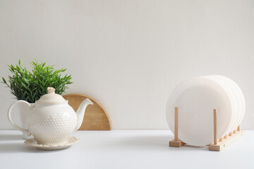 Plate rack, teapot and houseplant on white kitchen counter