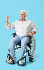 Happy mature man in wheelchair on blue background