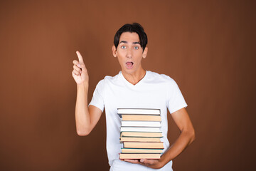 Funny student posing with books in studio on brown background.