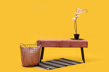 Pink bench with flowers and basket on yellow background