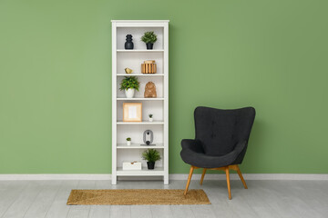 Modern shelf unit with black armchair and carpet near green wall