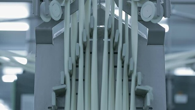 Cotton yarn moves along the rollers of spinning machines. Textile factory equipment for yarn production.