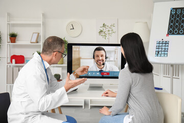 Mature doctor with patient video chatting in clinic