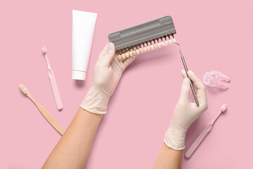 Dentist with teeth color samples on pink background