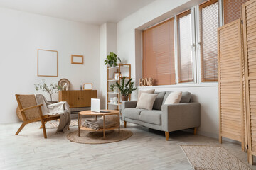 Interior of modern living room with grey sofa, armchair and laptop on coffee table