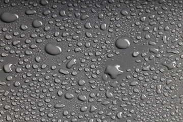 photo of irregularly shaped water droplets with various shapes on a black surface