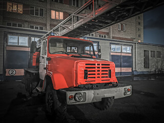 Old firetruck on the background of an old building at night