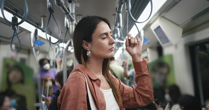 Commuting in public subway to work or going out party. Cinematic movie shot of young woman stand in dark subway when its on the move. subway , safety transport concept