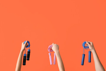 Female hands with skipping ropes on orange background - obrazy, fototapety, plakaty