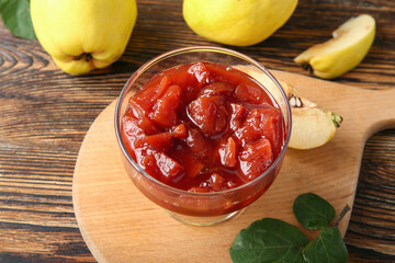 Bowl with jam and quince fruits on wooden background, closeup