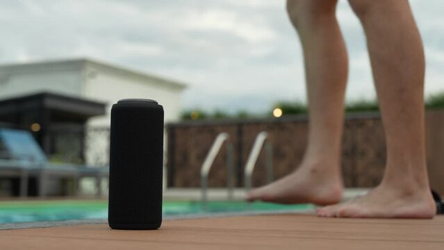 Boy at the pool chilling with music from his Bluetooth speaker at his side.