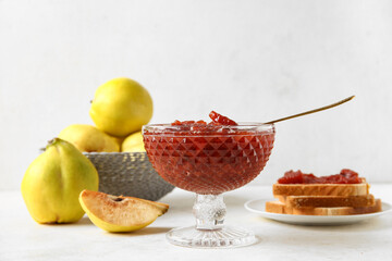 Bowl of sweet jam with quince fruits and toasts on white table