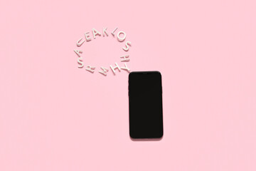 Mobile phone with blank screen and speech bubble made from letters on pink background