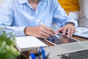 Fototapeta premium Closeup professional businessman hand pen writing work document strategy on tablet technology indoor workplace office table, adult entrepreneur business man manager person note finance report notepad