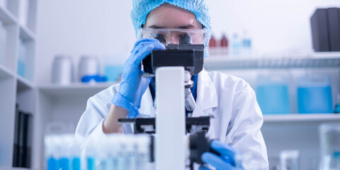 Professional female chemist technician looking microscope research discovery laboratory...