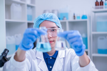 Fototapeta premium Professional expertise woman research scientist compare blue liquid in test tube or glassware beaker in chemical scientific experiment laboratory, female doctor pharmacy biology medicine person