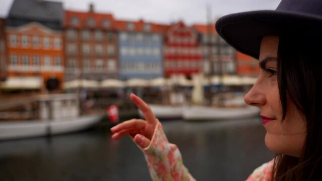 Close up on face of woman pointing at typical Danish houses with her finger, Nyhavn