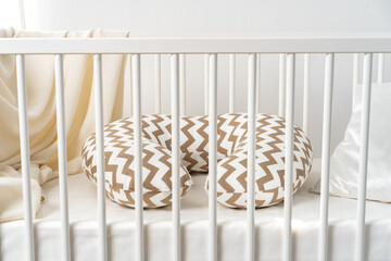 Fototapeta na wymiar White wooden baby crib with pillow in nursery room