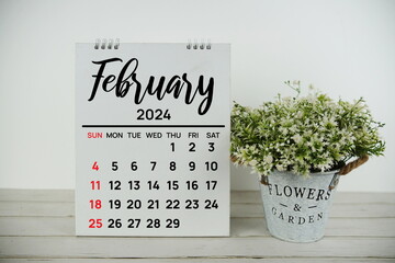 February 2024 monthly calendar with vintage alarm clock on wooden background - obrazy, fototapety, plakaty