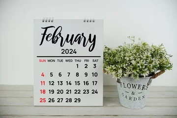 Fotobehang February 2024 monthly calendar with vintage alarm clock on wooden background © may1985