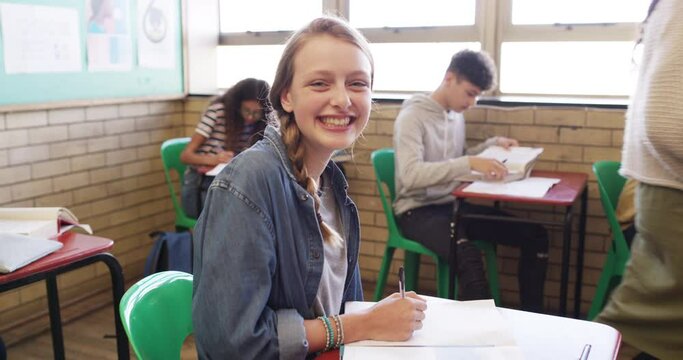 Happy girl, teen and student writing in classroom for test, project or exam with teacher at school. Face, portrait or young female person smile in education, learning or lesson for future development