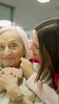 Smiling nurse kissing and embracing a senior woman in geriatric