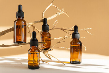 Serum in amber-colored glass vials with dropper lid on brown background. Essential oil for care of...