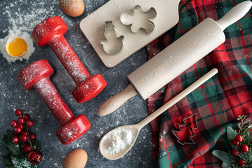 Healthy Christmas baking flat lay concept. Dumbbells, rolling pin and spoon kitchen utensils, dough...