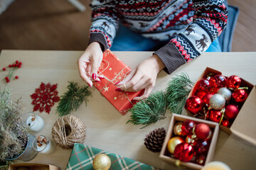 Woman in knitted sweater wrapping christmas presents with eco paper girl packing christmas gifts Xmas holiday concept