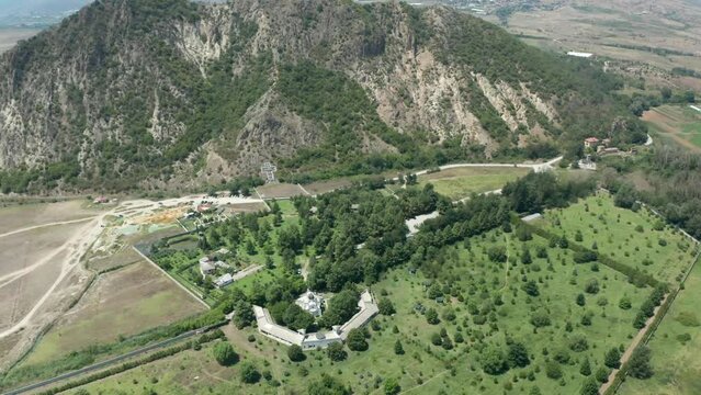A slow pull-out aerial drone shot of St. Petka church including the huge cross structure, at the foot of Mount Kozhuh, in the town of Rupite, Petrich, in Bulgaria.