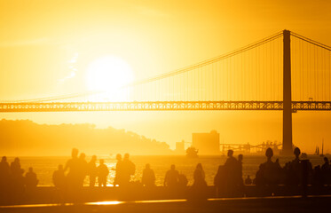 A Serene Sunset Overlooking a Majestic Bridge, With a Group of People in the Foreground