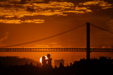 Sunset Romance: A Couple's Kiss by the Bridge at Dusk