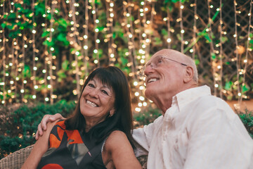 Happy relaxing moments for a senior couple sitting outdoors in the garden exchanging cuddles....