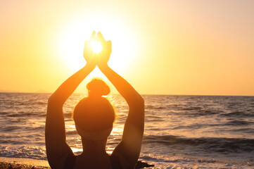 Woman's hands symbolizing prayer and gratitude. Mudra. Yoga concept. Silhouette of female hands on sun background. Beautiful scene