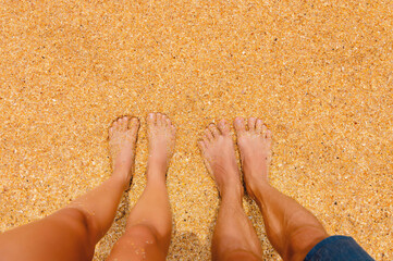 man and a woman stand barefoot on the sand on the beach. Pair of feet in nature, summer vacation trip, outdoor date. Close-up, first person view