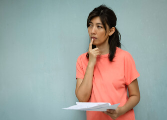 Woman hold paper chart in hand .touch her lip with finger and thinking with seriously feeling