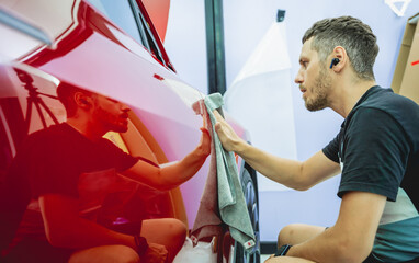 The process of installing protective film on the new red car.