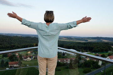 Fototapeta na wymiar A woman on the observation deck with her arms outstretched embraces the view of the landscape