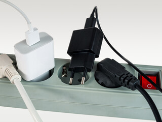 Various electrical plugs from electrical appliances connected to an extension cord isolated on a...
