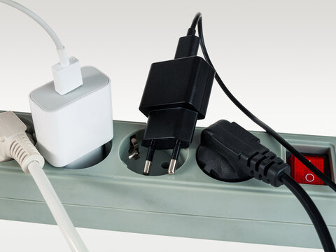 Various electrical plugs from electrical appliances connected to an extension cord isolated on a white background
