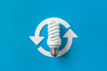 Energy saving light bulb and recycle arrows. Economical consumption of electricity. Blue background . The concept of nature conservation and renewable energy sources
