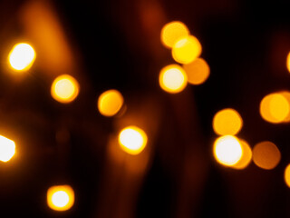 Blurred out-of-focus bright lights of a garland on a dark background close-up